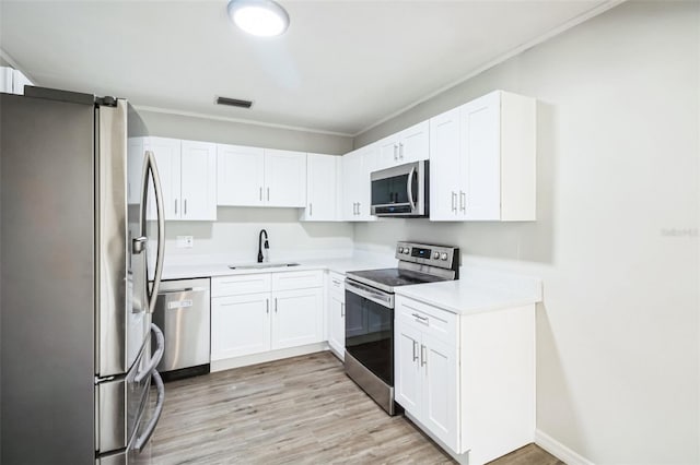 kitchen featuring visible vents, light wood-style flooring, a sink, appliances with stainless steel finishes, and light countertops