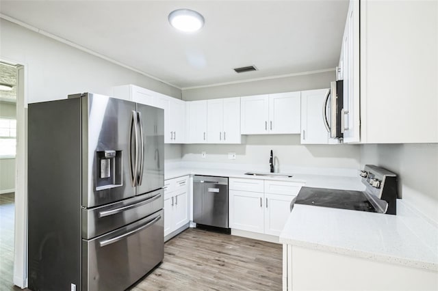 kitchen with crown molding, light wood-style flooring, appliances with stainless steel finishes, white cabinets, and a sink