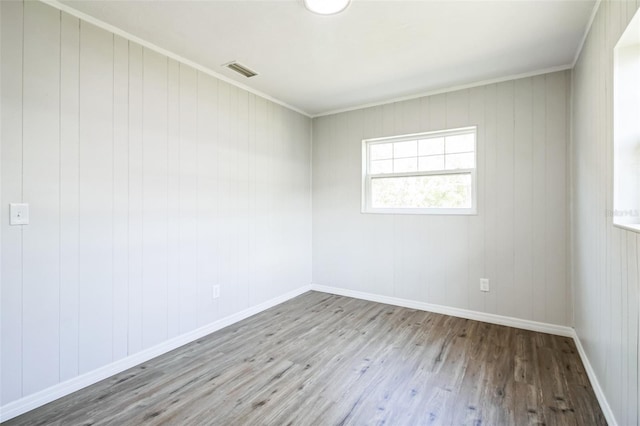 unfurnished room featuring visible vents, baseboards, wood finished floors, and crown molding