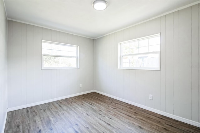 empty room featuring a healthy amount of sunlight, baseboards, and wood finished floors