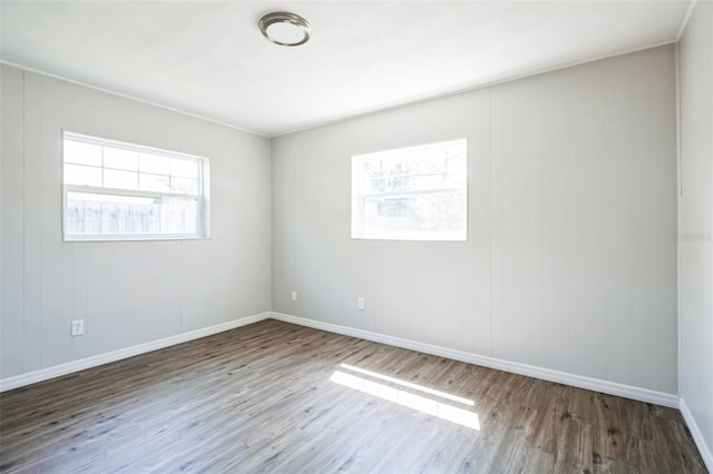 spare room with baseboards and wood finished floors