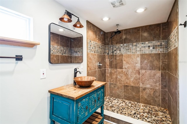 full bath featuring recessed lighting, visible vents, vanity, and a tile shower