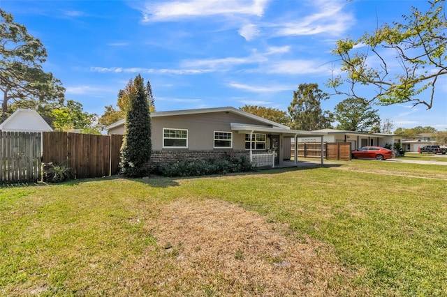 back of property featuring a yard, an attached carport, brick siding, and fence