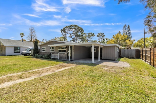 rear view of property with a carport, a lawn, and fence