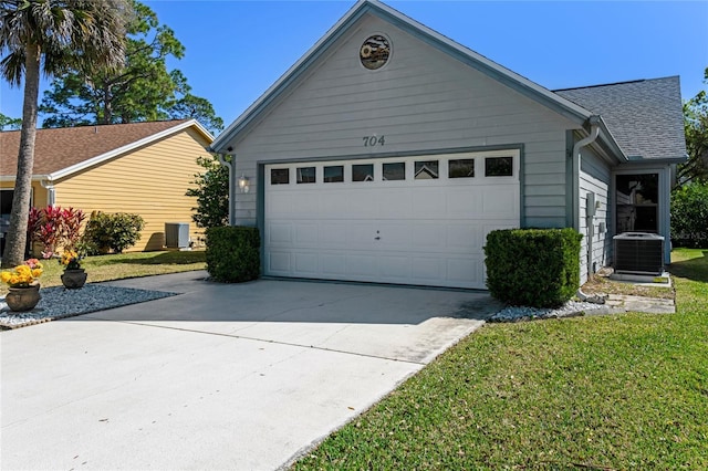 exterior space with concrete driveway, roof with shingles, central AC unit, a lawn, and an attached garage