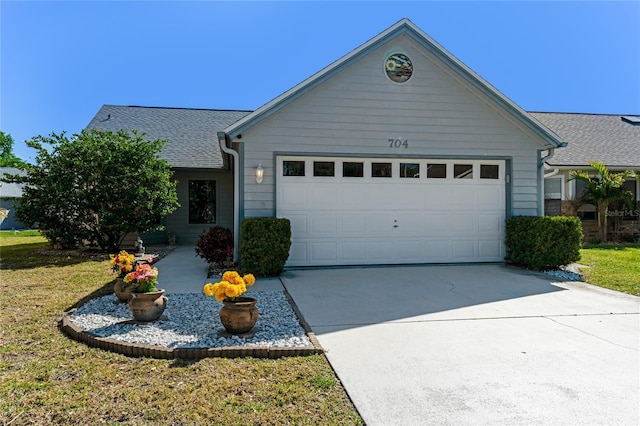 ranch-style home with a garage, a front yard, driveway, and a shingled roof