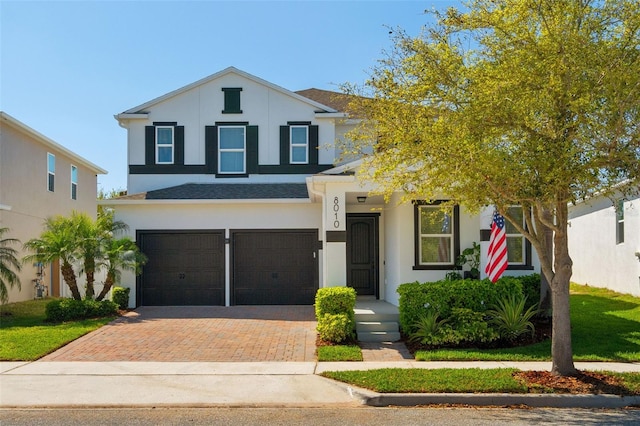 view of front of home featuring decorative driveway, a garage, and stucco siding