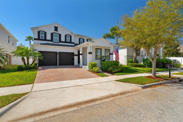 view of front of property featuring a front yard, decorative driveway, a garage, and stucco siding