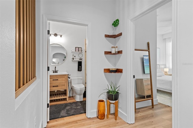 corridor with baseboards, light wood finished floors, and a sink