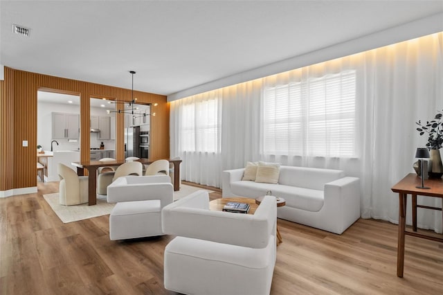 living area with a notable chandelier, visible vents, and light wood-style floors