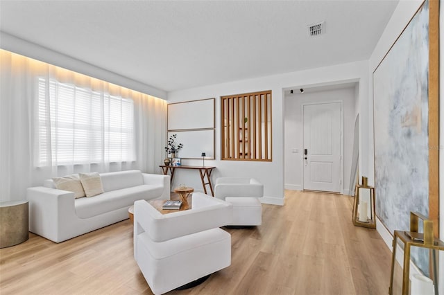 living area featuring light wood-style flooring, baseboards, and visible vents