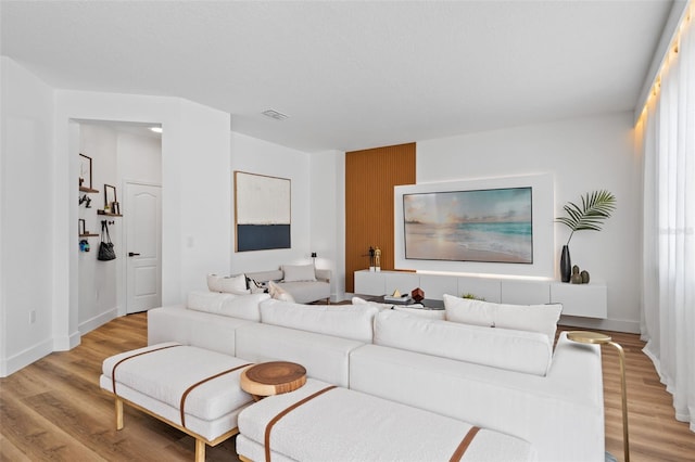 living area featuring visible vents, light wood-style flooring, and baseboards