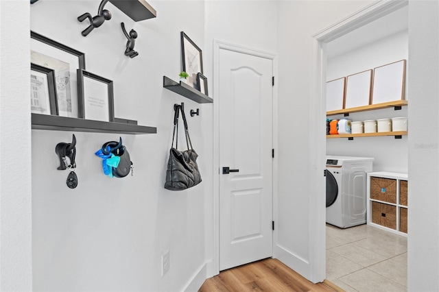 laundry area with light wood-type flooring, washer / clothes dryer, baseboards, and laundry area