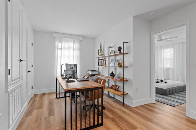 office space with visible vents, a textured ceiling, light wood-type flooring, and baseboards