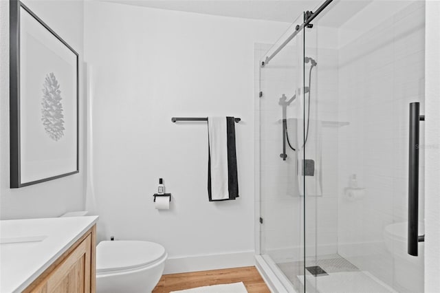 full bath with vanity, wood finished floors, baseboards, a shower stall, and toilet