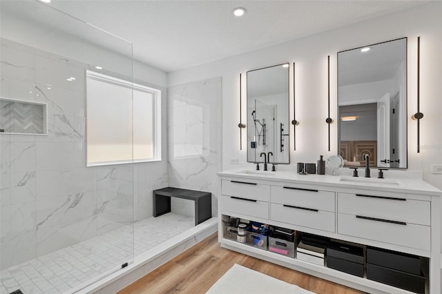 full bathroom featuring a marble finish shower, double vanity, wood finished floors, and a sink