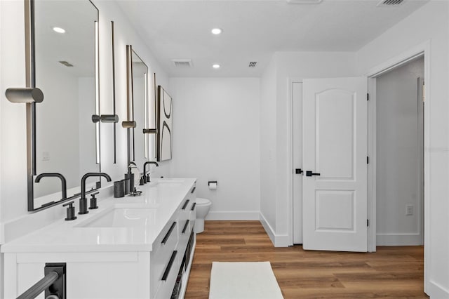 bathroom featuring a sink, visible vents, wood finished floors, and recessed lighting