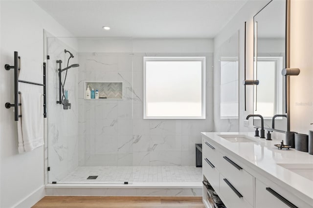 full bath featuring a marble finish shower, recessed lighting, double vanity, and a sink