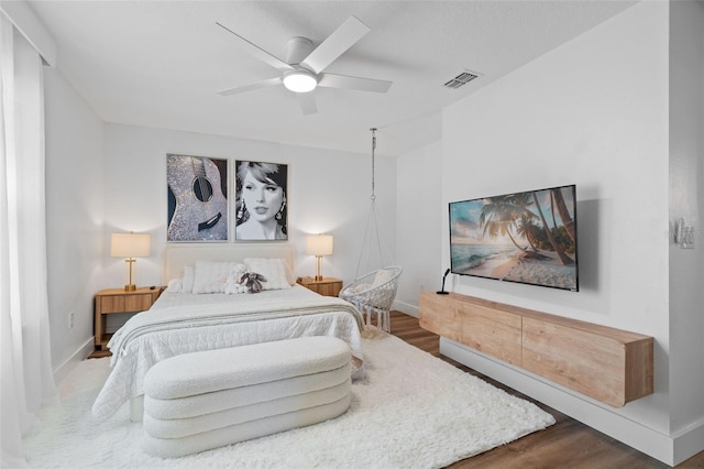 bedroom featuring a ceiling fan, wood finished floors, visible vents, and baseboards