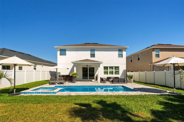 rear view of house with stucco siding, a lawn, a fenced backyard, a fenced in pool, and a patio area