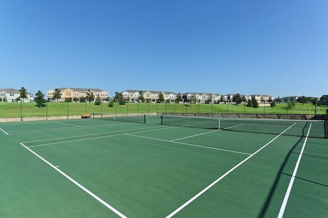 view of tennis court featuring fence and a residential view