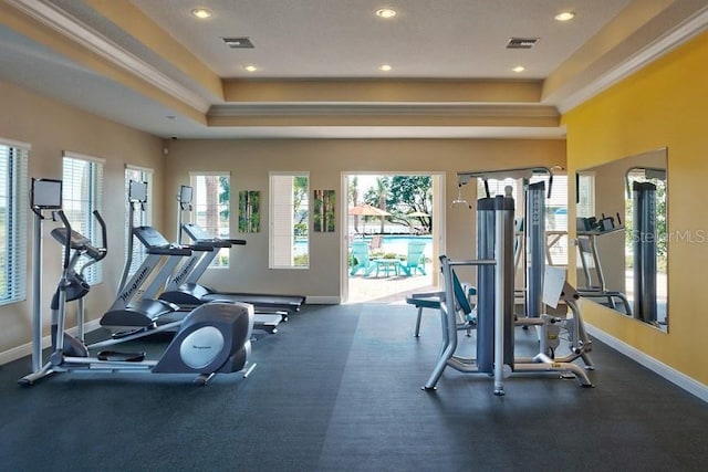 workout area with visible vents, a raised ceiling, baseboards, and crown molding