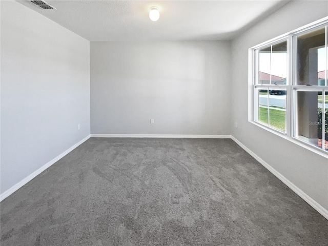 carpeted empty room with visible vents and baseboards