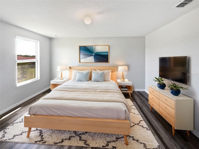 bedroom with visible vents, baseboards, and dark wood-style flooring