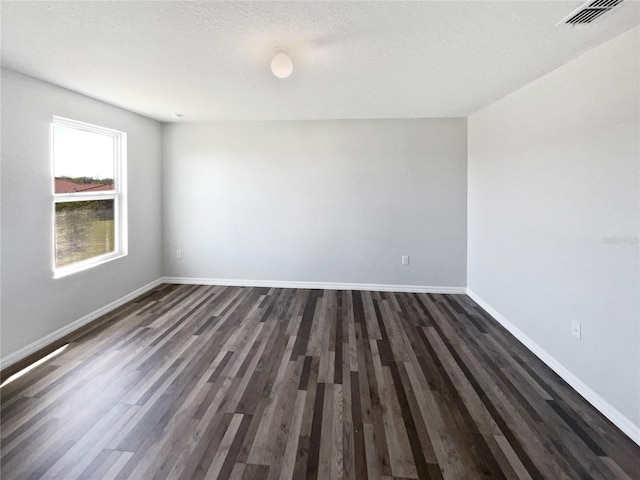 unfurnished room featuring dark wood finished floors, visible vents, a textured ceiling, and baseboards