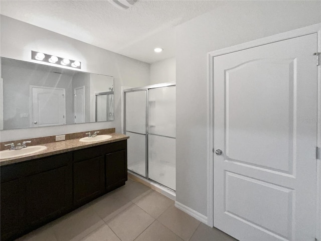 bathroom with double vanity, tile patterned floors, a stall shower, and a sink