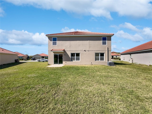 rear view of house with stucco siding, a lawn, a tile roof, a patio, and cooling unit