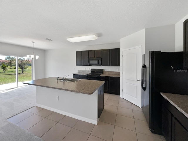 kitchen featuring visible vents, black appliances, a kitchen island with sink, pendant lighting, and a sink