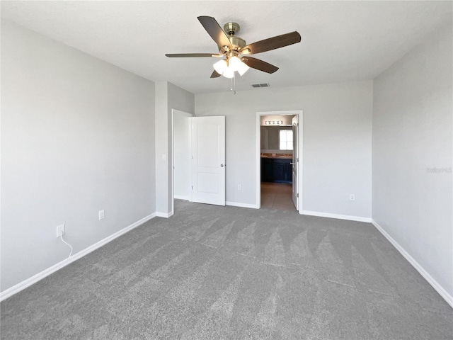 unfurnished bedroom featuring visible vents, dark carpet, ensuite bath, and baseboards