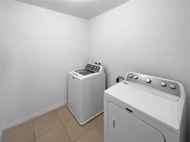 washroom featuring light tile patterned floors, baseboards, separate washer and dryer, and laundry area