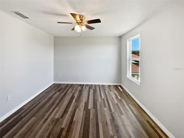 empty room with dark wood finished floors, baseboards, visible vents, and ceiling fan