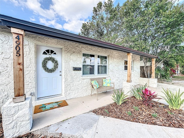 property entrance with covered porch and stucco siding