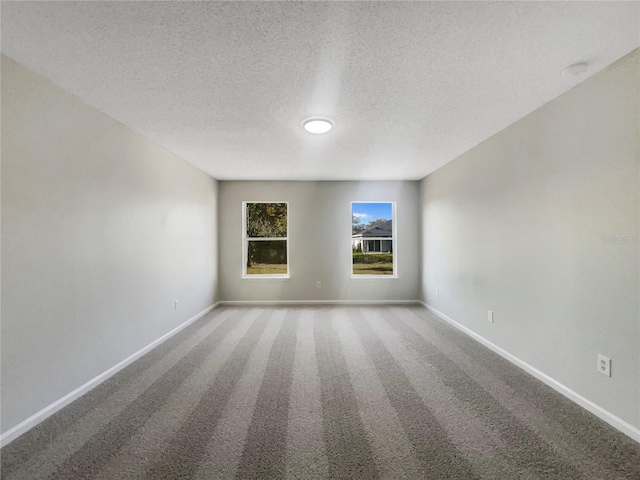 unfurnished room with carpet, baseboards, and a textured ceiling