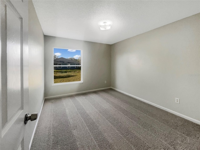 carpeted spare room featuring baseboards and a textured ceiling