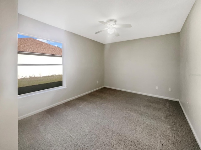 carpeted spare room featuring a ceiling fan and baseboards