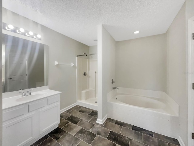 bathroom featuring a bath, a stall shower, vanity, and a textured ceiling