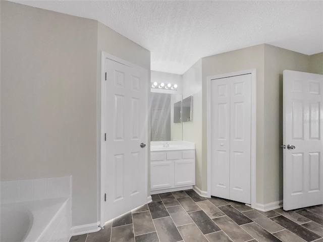 full bath with a tub, a textured ceiling, a closet, baseboards, and vanity