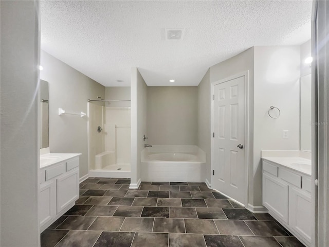 full bathroom featuring visible vents, two vanities, a stall shower, baseboards, and a bath