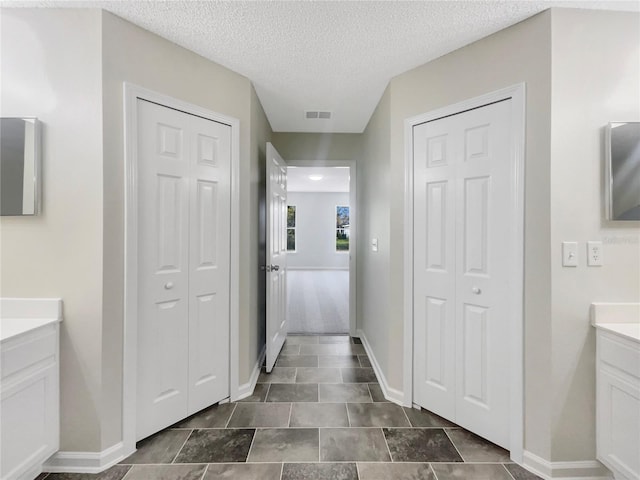 bathroom with vanity, visible vents, a closet, and a textured ceiling