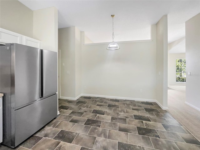 kitchen featuring white cabinetry, decorative light fixtures, baseboards, and freestanding refrigerator