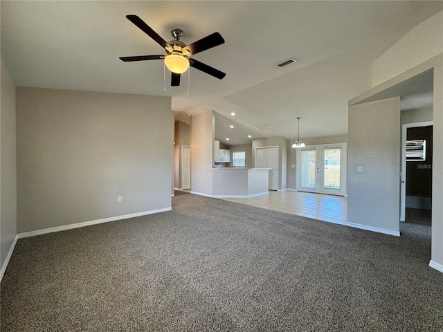 unfurnished living room featuring visible vents, baseboards, vaulted ceiling, carpet floors, and ceiling fan with notable chandelier