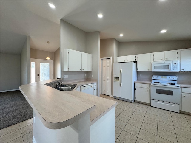 kitchen featuring white appliances, a peninsula, lofted ceiling, a sink, and light countertops