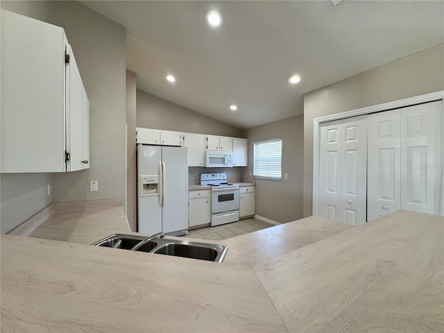 kitchen featuring white appliances, recessed lighting, a sink, vaulted ceiling, and white cabinets