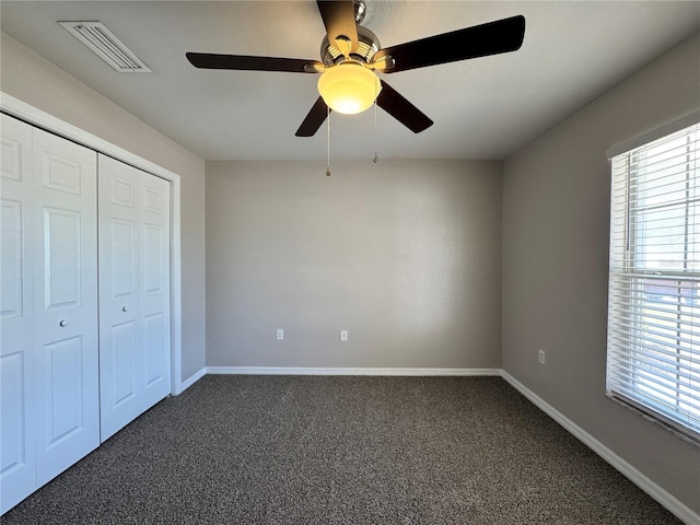 unfurnished bedroom featuring a closet, baseboards, visible vents, and dark colored carpet