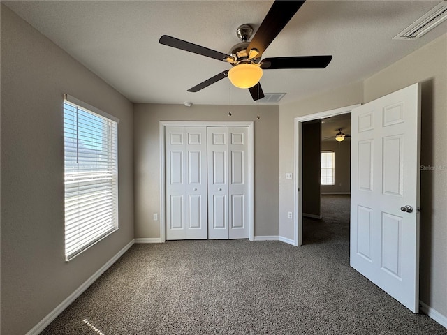 unfurnished bedroom featuring baseboards, visible vents, ceiling fan, a closet, and carpet flooring