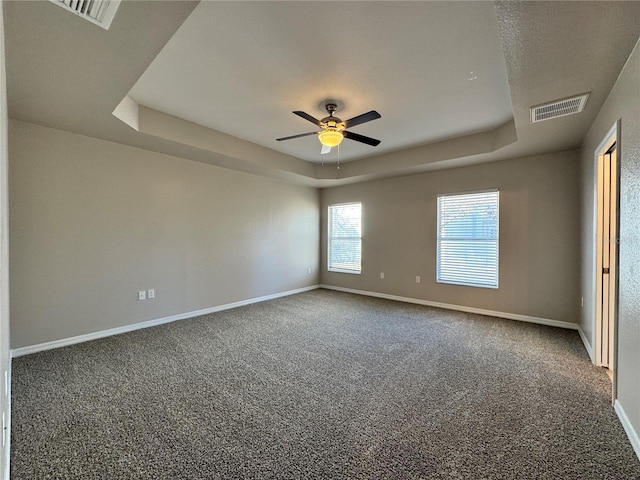 spare room with visible vents, a raised ceiling, baseboards, and a ceiling fan